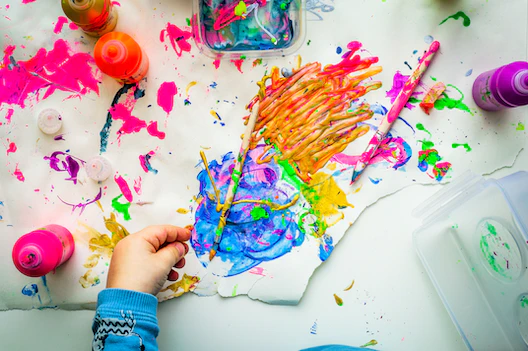 Child paints abstractly with brush and hands