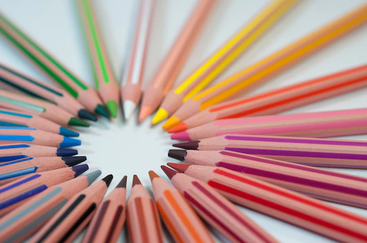 Colored pencils arranged in a circle with their tips pointed inwards.